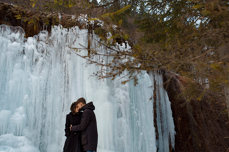 Imbratisarea unui cuplu in fata unei cascade inhetate
