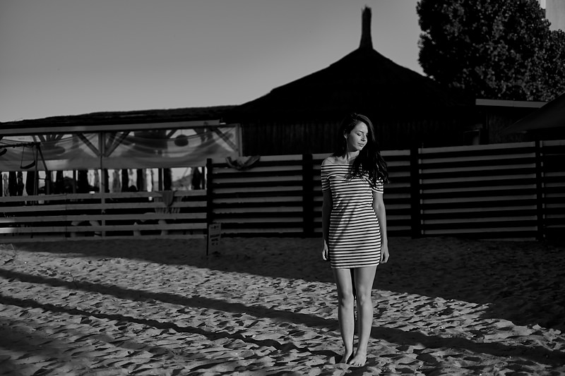 Fotografie al-negru cu adolescenta in soare imbracata intr-o rochita dungata